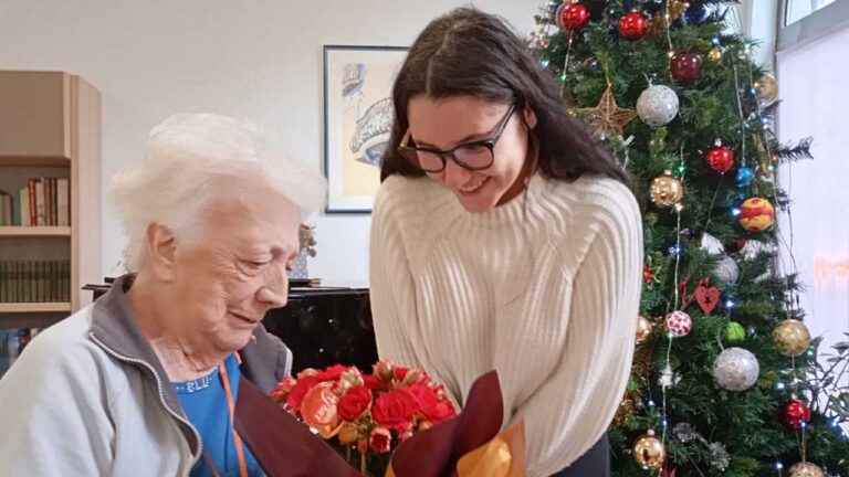 Anziana riceve mazzo di fiori da nipote di Babbo Natale