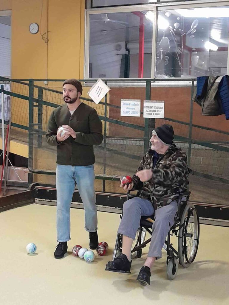 Anziano in carrozzina gioca a bocce con nipote di Babbo Natale